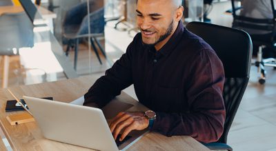 A professional works at a laptop in an office setting.