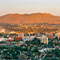 Panorama of a desert city with palm trees against a golden sky