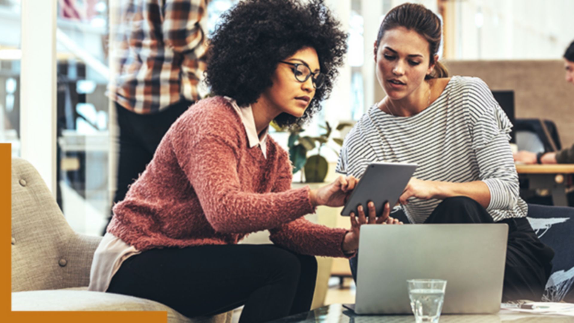 Two people sitting in a coffee shop working with GIS software on a tablet and laptop