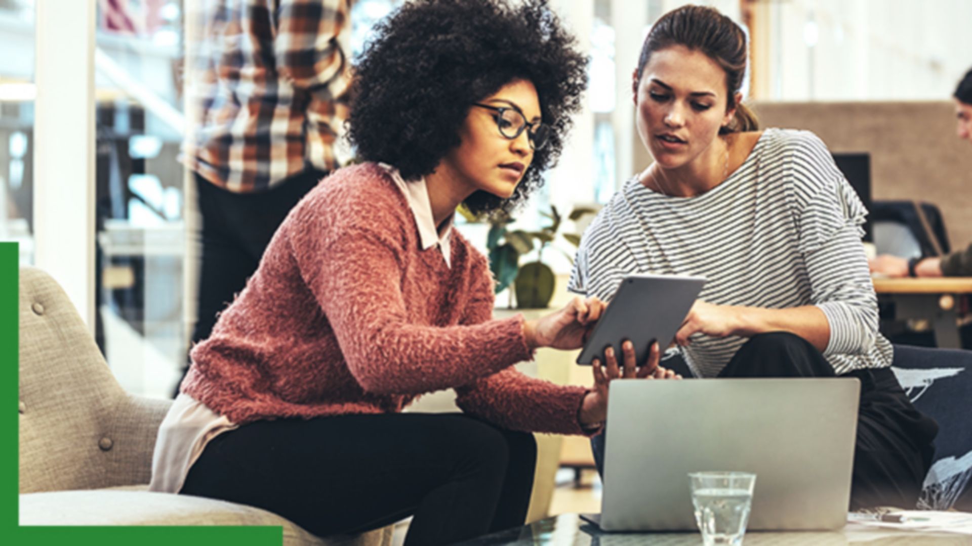 Two people sitting in a coffee shop working with GIS software on a tablet and laptop