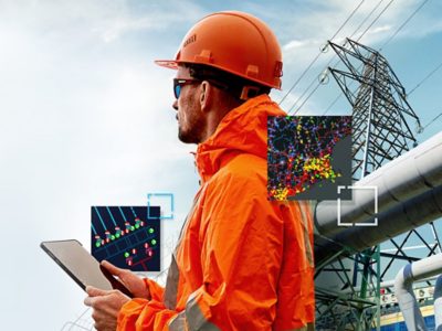 Person in an orange coat and orange hard hat holding a tablet with energy utility maps