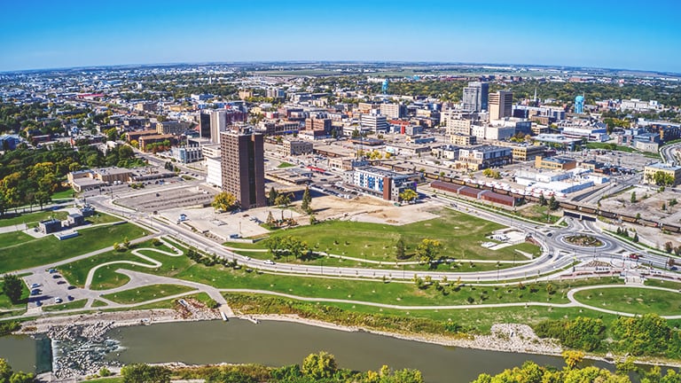 Aerial view of a sprawling cityscape stretching into a flat horizon under a clear blue sky