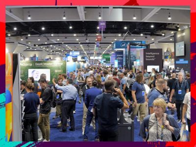 Wide view of a crowded and lively Expo hall with numerous booths, banners, and attendees