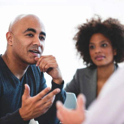 Two people communicating and one person looking on in the background