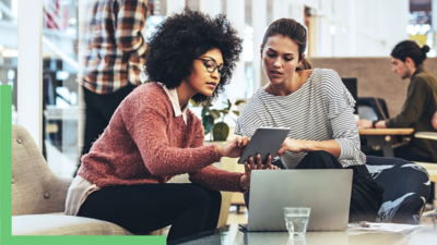 Two people sitting together using a laptop and a tablet