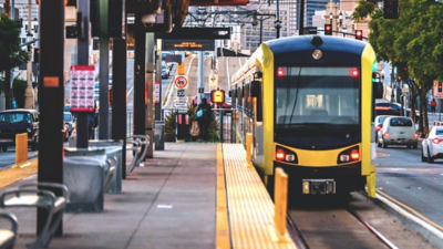 An outdoor metro station with a yellow electric-powered train pulling in