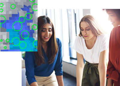 Two people standing in an office working together with a digital map showing areas circled in green in the foreground